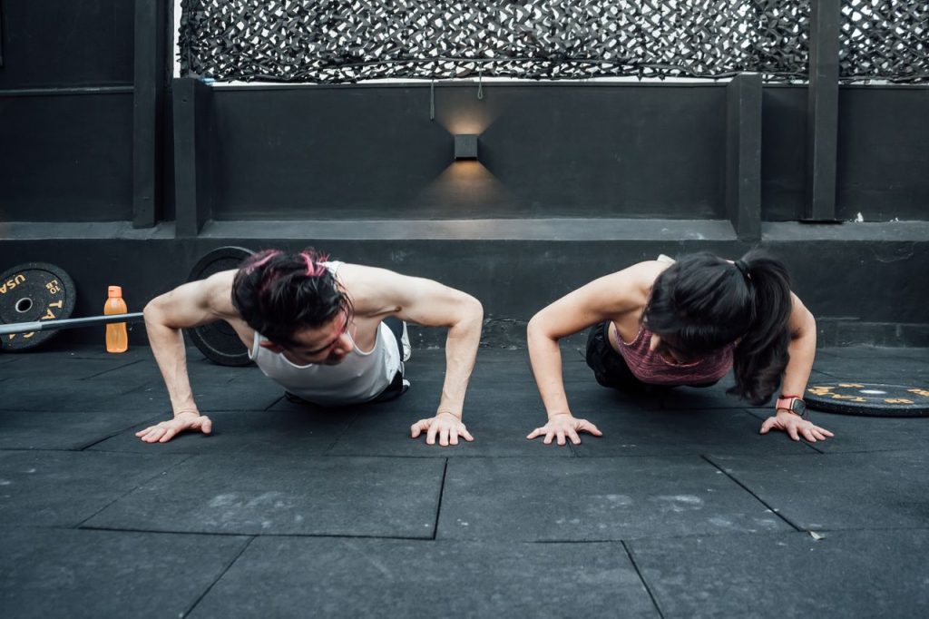 Two adults doing push-ups in an indoor gym setting in Mexico City, promoting a fit and healthy lifestyle.