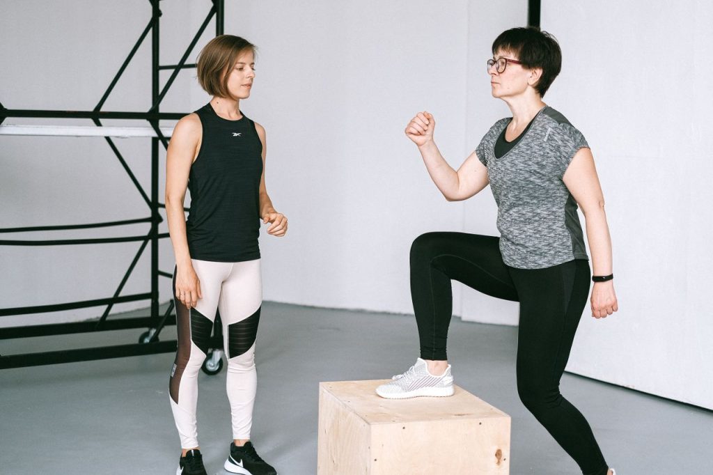 Fitness coach guides a woman in workout indoors. Focus on exercise and healthy lifestyle.