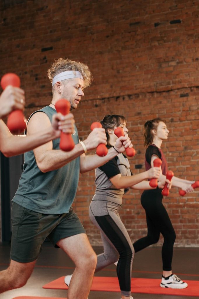 Diverse group exercising with dumbbells in an indoor gym setting, promoting healthy lifestyle.